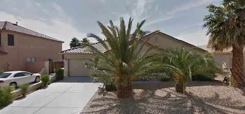 Exterior view of Arizona Buttes Assisted Living Home with palm trees and a driveway.
