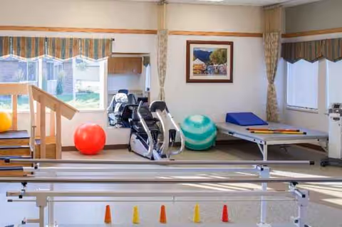 Interior rehab gym with exercise equipment, mats, and windows at Mountain View Health and Rehabilitation.