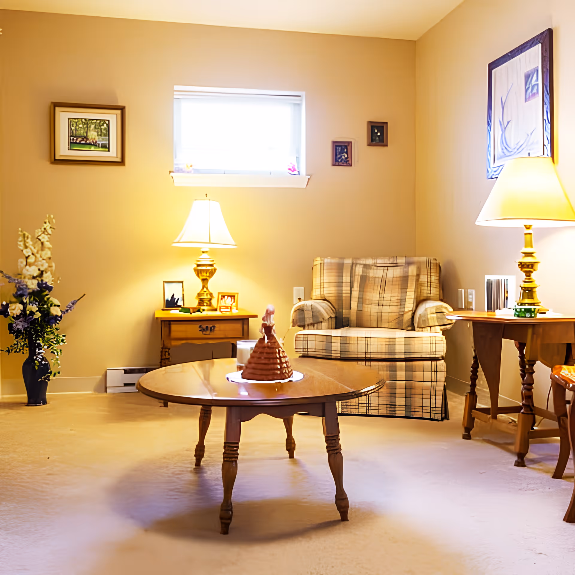 A cozy living room with a plaid armchair, wooden coffee table, side tables with lamps, and a floral arrangement.