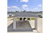 Covered entrance area with a pitched roof supported by white brick columns at Elgin Nursing and Rehabilitation Center, with a clear blue sky and parts of the building visible in the background.