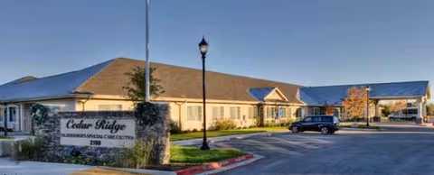 Exterior view of Cedar Ridge Alzheimer's Special Care Center with parking lot and sign.
