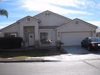 Front exterior of a single-story care home with a driveway and parked car.