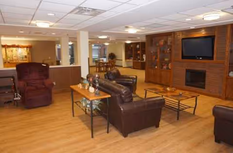 Senior living common area with brown leather seating, coffee tables, and a fireplace.