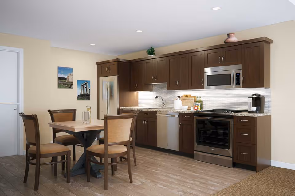 Kitchen with dark wood cabinets, stainless appliances, and a four-seat dining table.