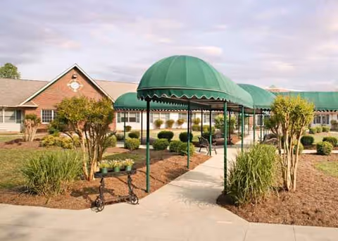 Exterior view of Cornerstone Village with green canopies, walkway, and manicured landscaping.