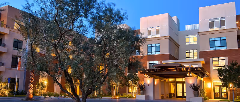 Evening exterior view of The Village at NorthRidge with illuminated entrance and trees