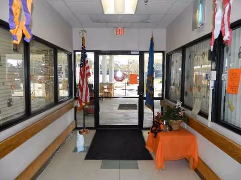 Interior hallway entrance with glass doors, American flags, and an orange table covered near the exit.