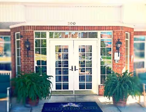Exterior front entrance of a brick building with double doors, plants, and address 200.