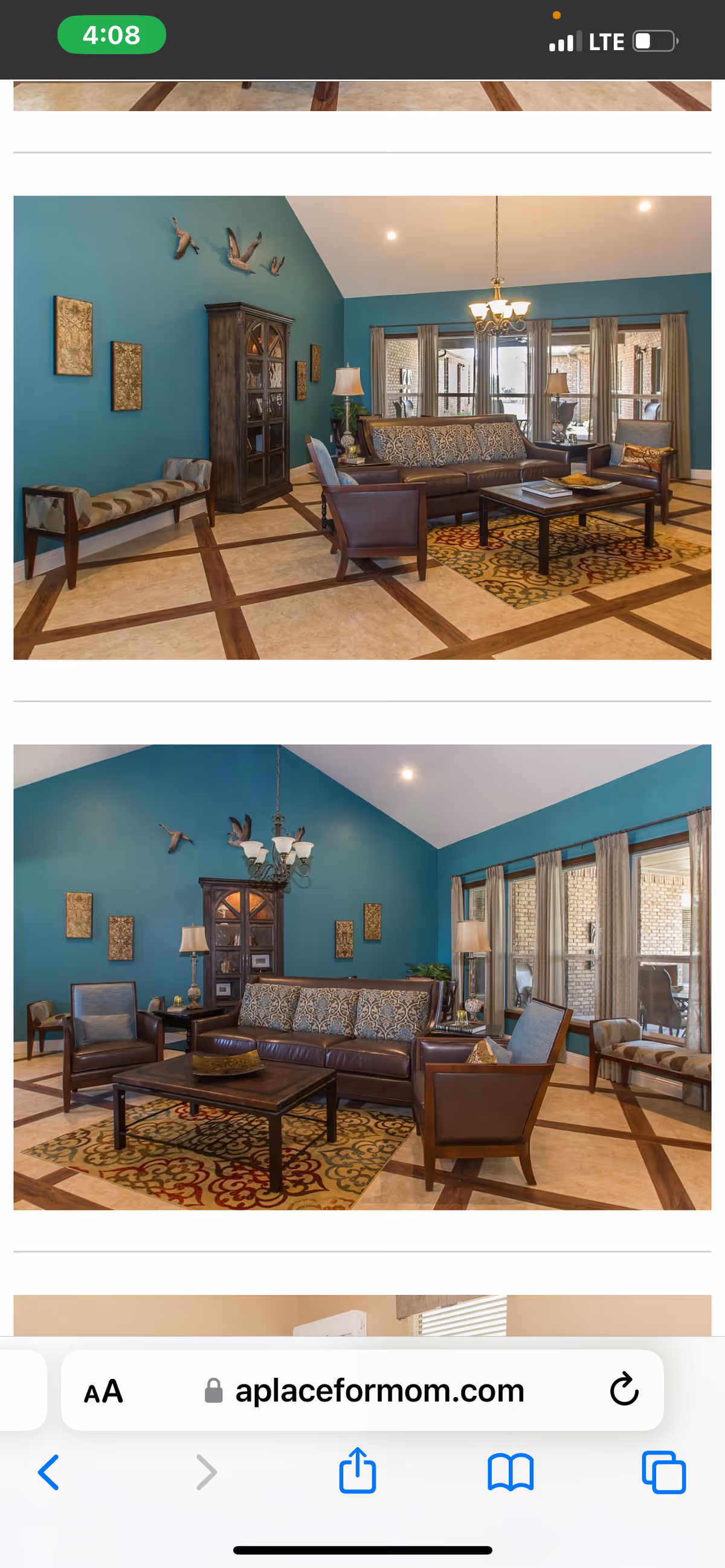 A spacious living room with teal walls and a high vaulted ceiling. The room features a brown leather sofa with patterned cushions, two matching armchairs, a wooden coffee table on a decorative rug, and a wooden cabinet against the wall. There are wall decorations including three bird sculptures and framed art pieces. Large windows with beige curtains allow natural light to enter the room.