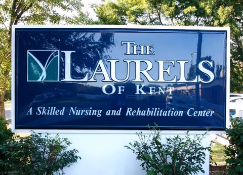 Blue sign reading The Laurels of Kent, a skilled nursing and rehabilitation center, outdoors.