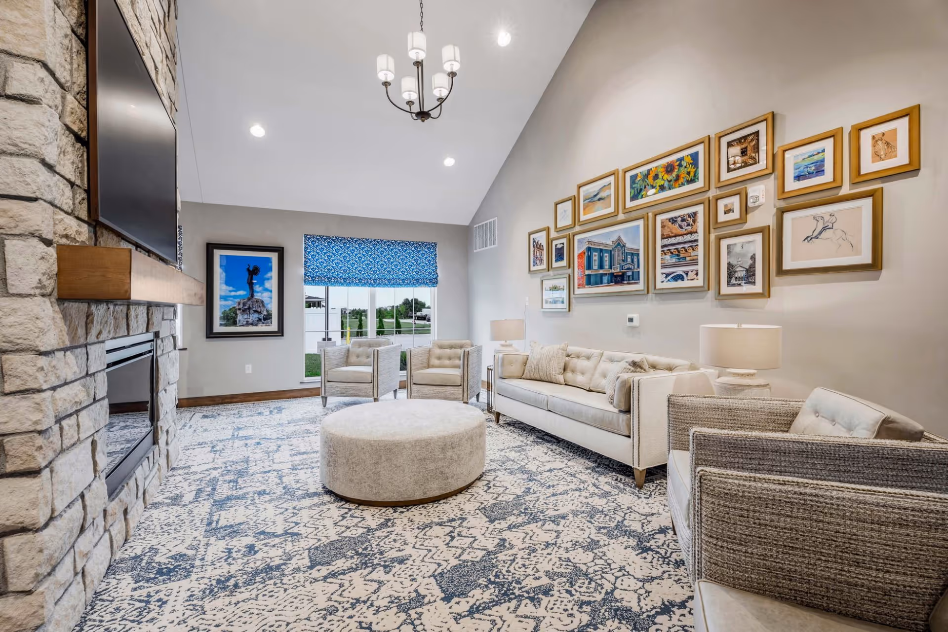 Bright furnished lounge with sofas, armchairs, a round ottoman, fireplace and a gallery wall of framed artwork.