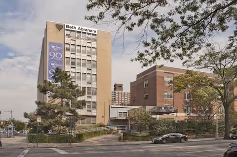 Exterior view of Beth Abraham Center building with trees and a parking lot.