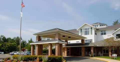 Front exterior of Holiday Devonshire Estates, showing the entrance canopy, flagpole, and parking.