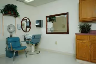 Care facility hair salon with chairs, mirrors, and cabinets.