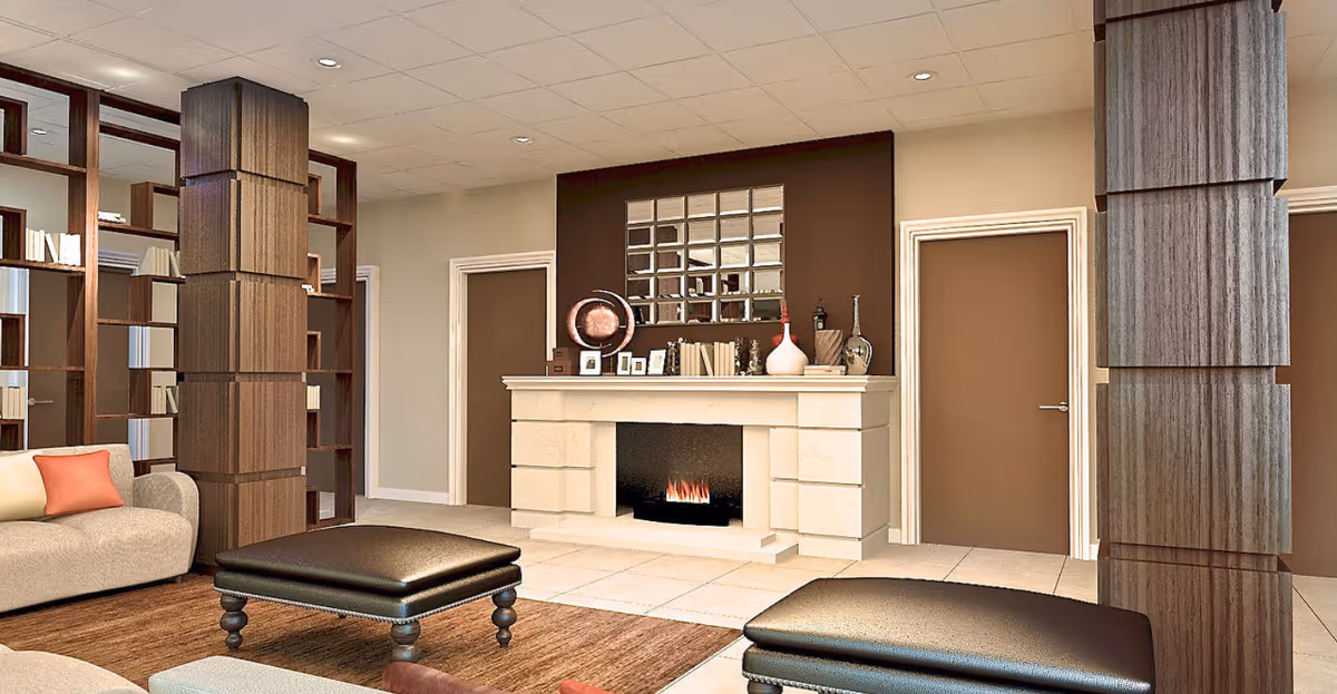 Communal living room with a central fireplace, upholstered seating, ottomans, and decorative shelving and columns.