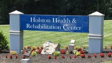 Outdoor sign for Holston Health & Rehabilitation Center with lawn and flowers