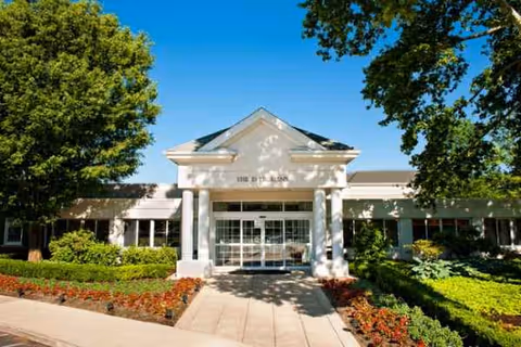 Front entrance of The Evergreens senior living facility with columns and landscaping.