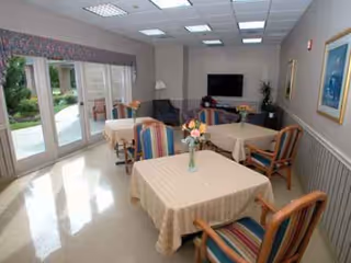 Interior dining area with multiple tables, striped chairs, and a TV on the wall.
