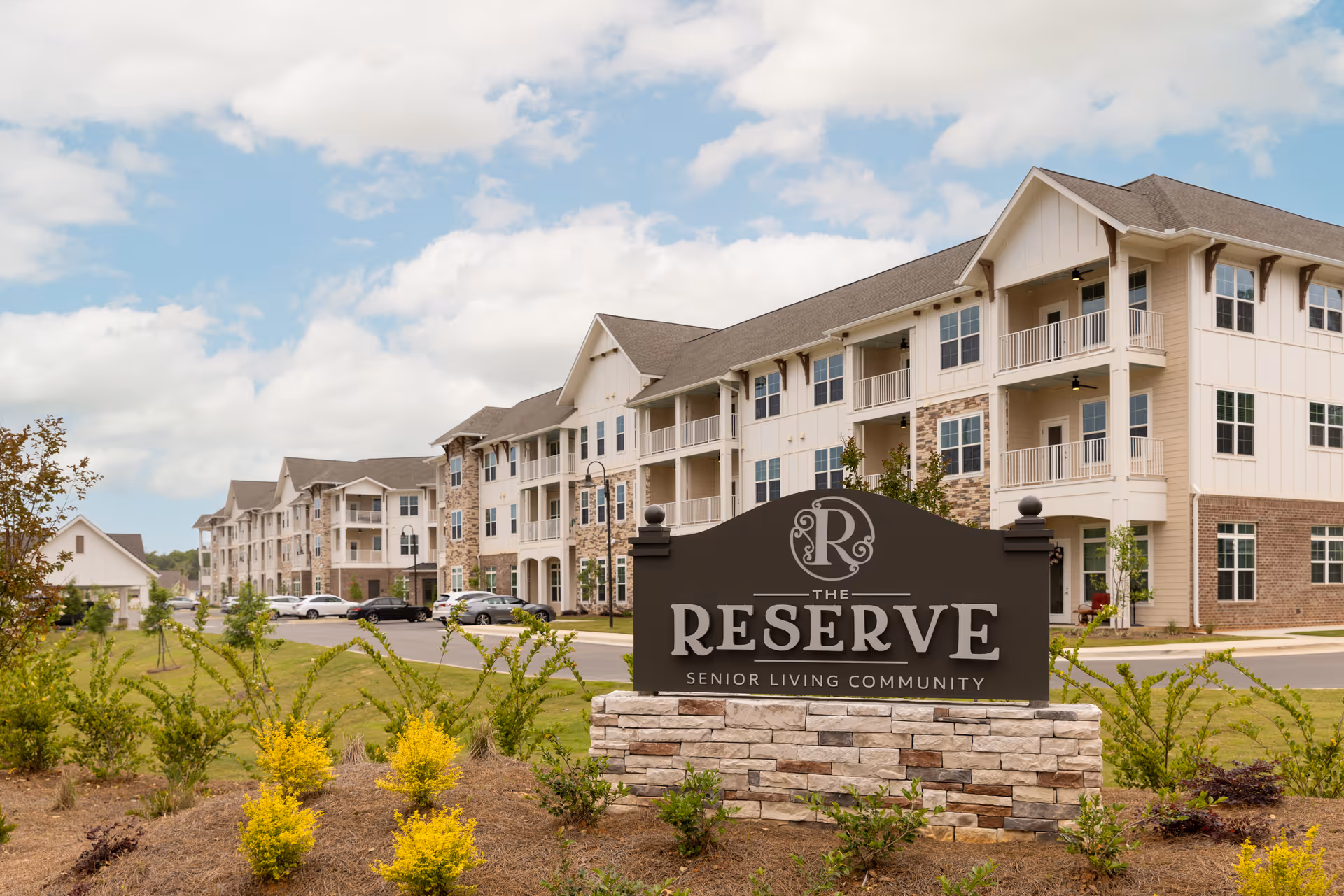 Exterior view of a multi-story senior living building with a stone sign reading "The Reserve" in the foreground.