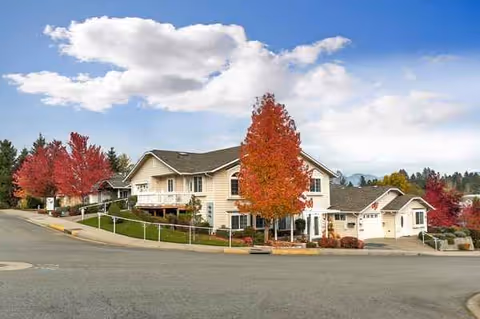 A beige senior living facility with attached garages and autumn-colored trees.