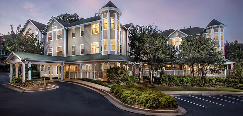 Exterior view of Winnwood Retirement Community at dusk with landscaped entrance.