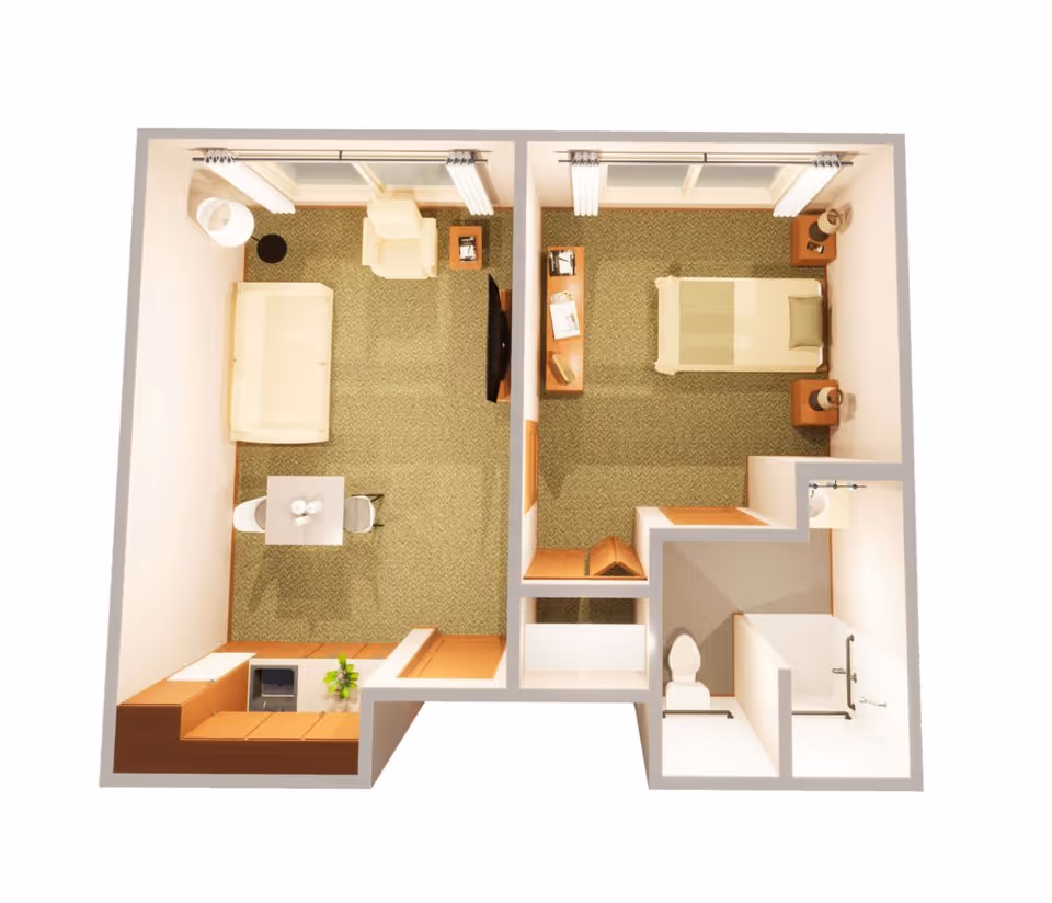 3D floor plan of a memory care facility unit with a living room, bedroom, kitchen area, and bathroom. The living room has a sofa, armchair, small dining table with two chairs, and a TV. The bedroom contains a single bed, two nightstands with lamps, and a dresser. The bathroom includes a toilet, sink, and walk-in shower.