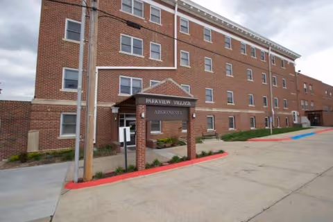 Brick senior living building with a covered entrance reading Parkview Village Apartments.