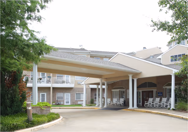 Covered entrance/portico of The Waterford at Mesquite with white columns, rocking chairs, and balconies on the building facade.