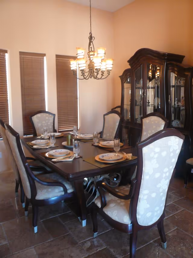 Formal dining room with a set table, upholstered chairs, a chandelier, and a china cabinet.