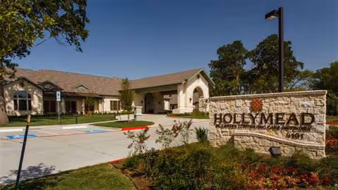 Exterior view of Hollymead senior living facility with a stone entrance sign.