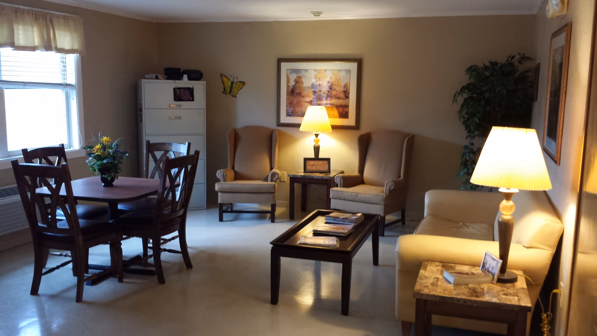 Interior living lounge with sofas, chairs, tables, lamps, and a dining table near the window.