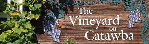 Wooden sign reading 'The Vineyard on Catawba' surrounded by grape vines.