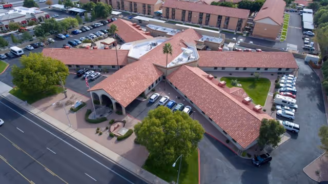 Aerial view of a single-story senior living facility with red tile roofs arranged in an X-shaped layout, central courtyard, and surrounding parking.