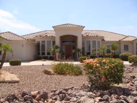 Single-story beige assisted living facility with a tiled roof, desert landscaping, and a front entrance.