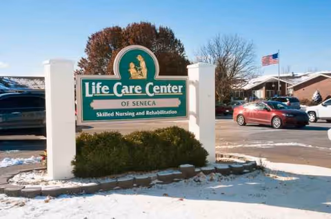 Outdoor view of Life Care Center of Seneca entrance sign with cars in snowy parking lot