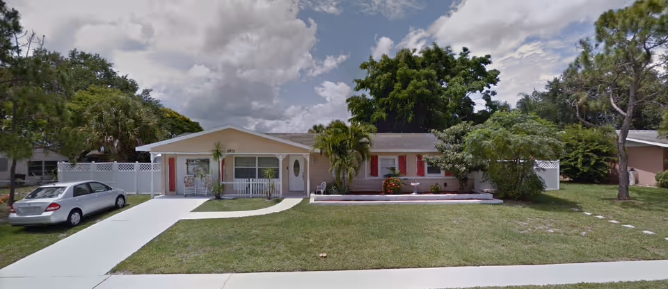 Front exterior of 'A Place Like Home' senior living house with driveway and parked car.