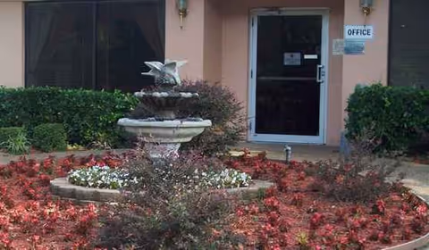 Front entrance of Twin Oaks Health & Rehabilitation Center with fountain and red flower beds.