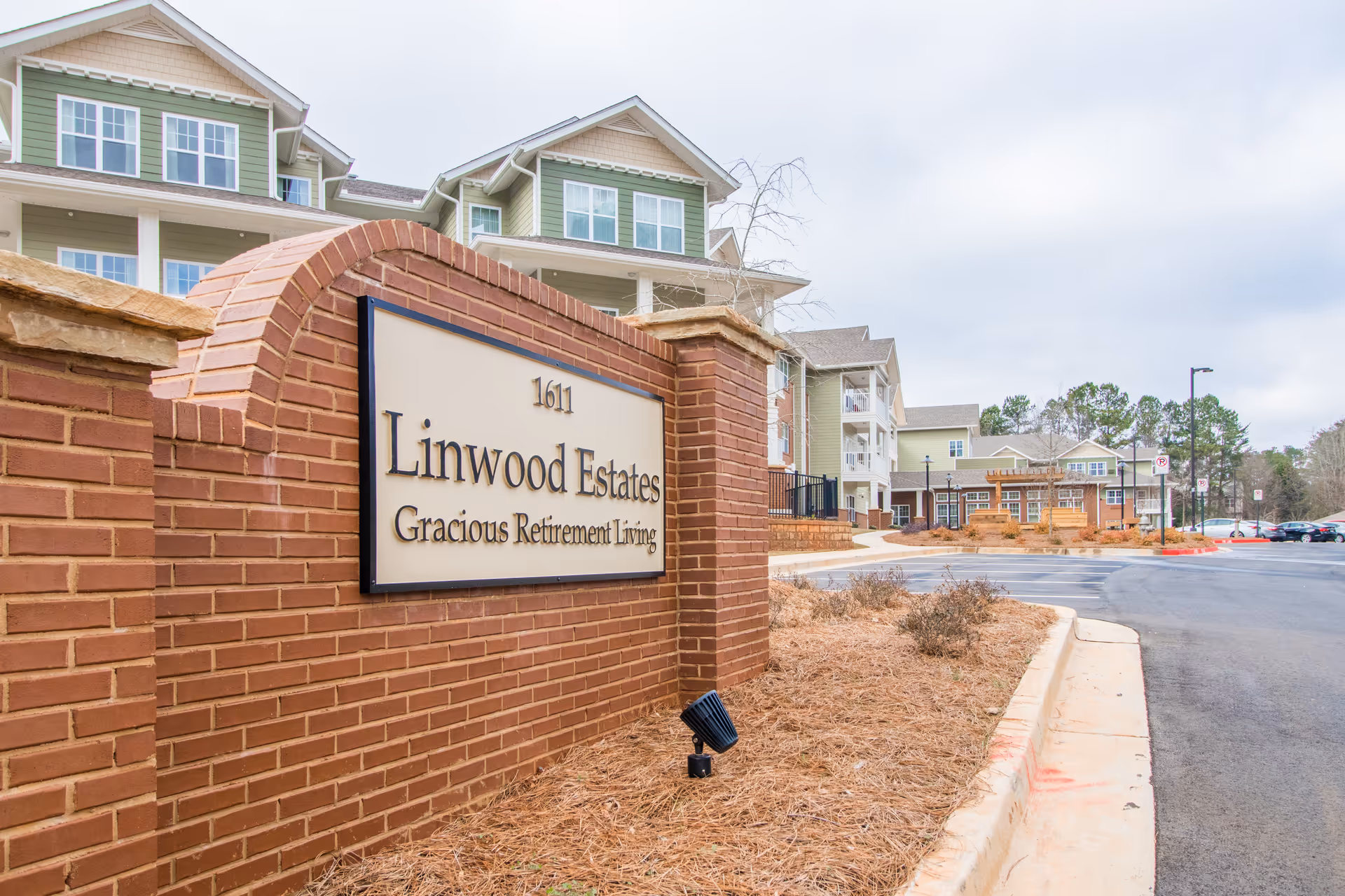 Brick entrance sign reading 'Linwood Estates Gracious Retirement Living' in front of multi-story retirement community buildings.