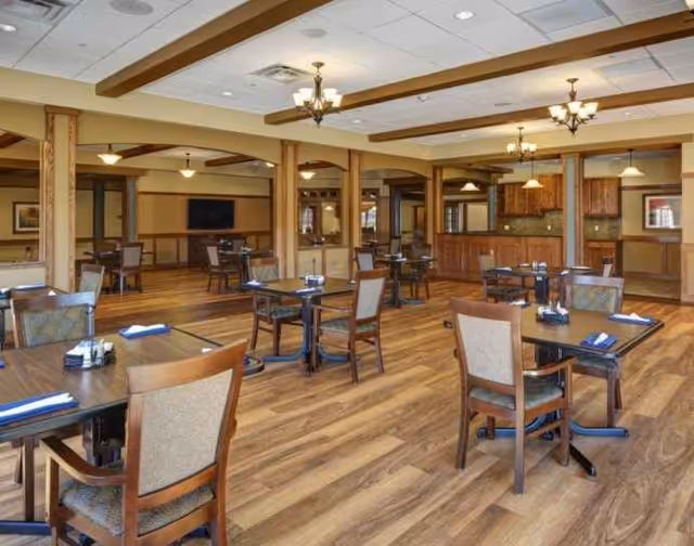 Wide, well-lit dining room with multiple wooden tables and chairs.