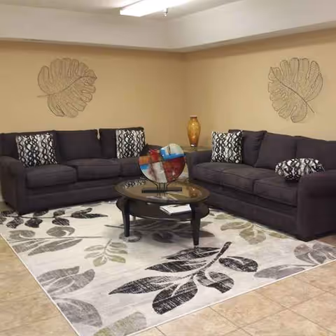 Two dark sofas form an L-shaped living room seating area with a glass coffee table.