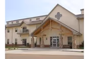 Exterior view of Benedictine Living Community-Dickinson entrance with beige walls and stone pillars