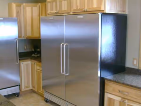 Kitchen scene with stainless steel refrigerator and wooden cabinetry at Culver Meadows Senior Living.