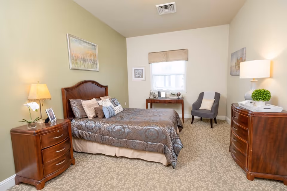 Well-appointed bedroom with a double bed, wooden nightstands and dresser, an armchair, and a window.