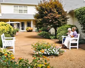Two people sitting on a bench in a landscaped courtyard outside a residential building.