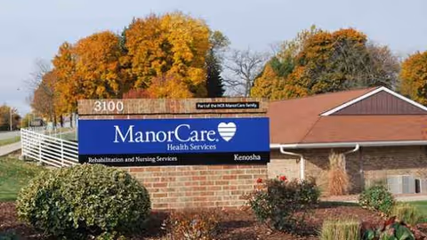 Exterior view of ManorCare Health Services sign in front of a brick building.