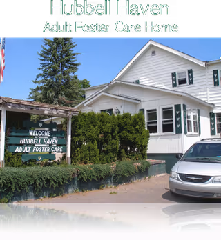 Front exterior of Hubbell Haven Adult Foster Care Home with a sign and car.