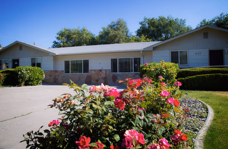 Single-story Comfortcare Inc exterior with rose bushes, driveway, and well-kept landscaping.
