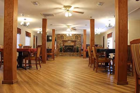 Spacious senior living dining area with tables, chairs, and a stone fireplace.