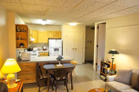 Open living area with dining table, kitchenette, and beige sofa.