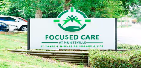Outdoor sign for Focused Care at Huntsville with green logo and landscaping.